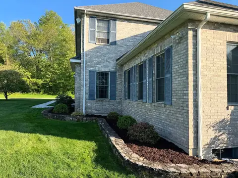 A low stone wall retaining a mulch bed along a brick house